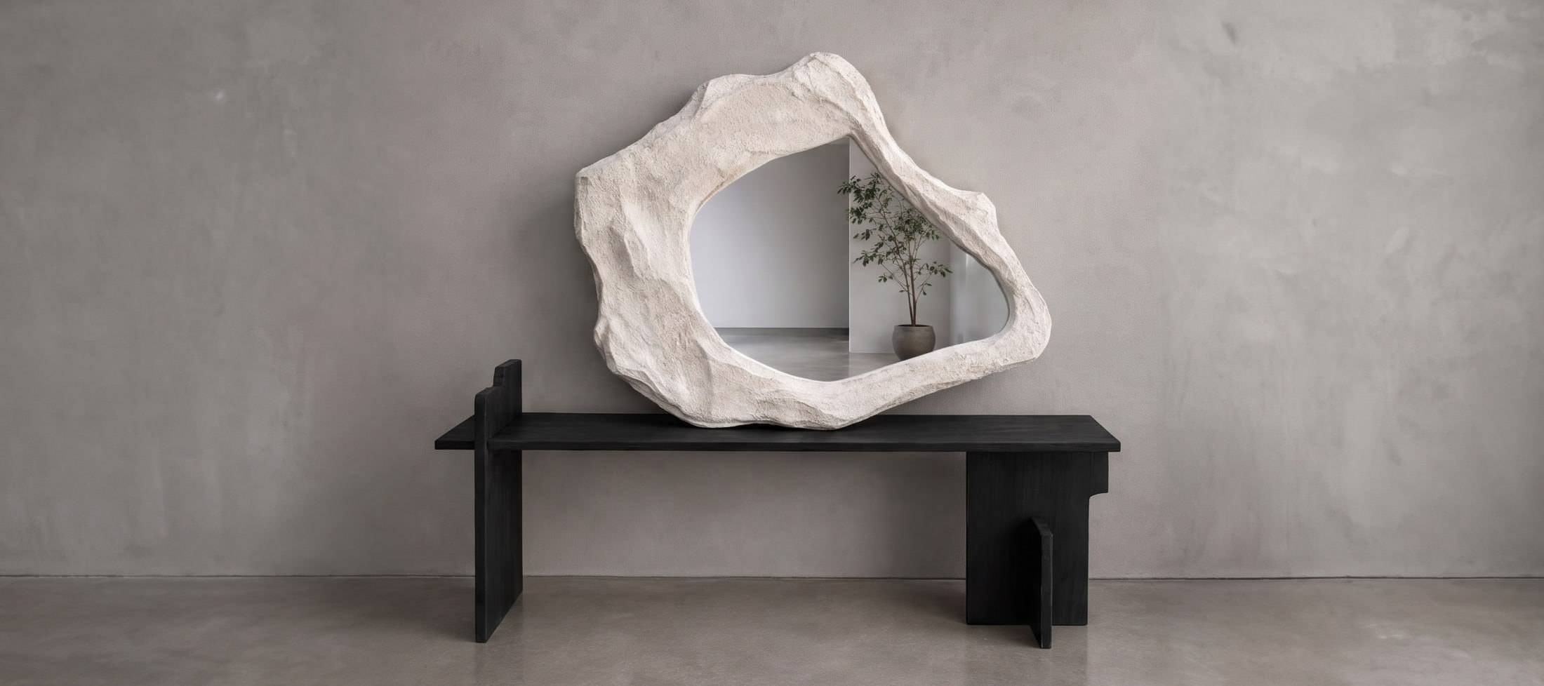 Origen, BN 005: espejo de contorno orgánico y superficie mineral ocupando el muro del espacio que lo recibe.